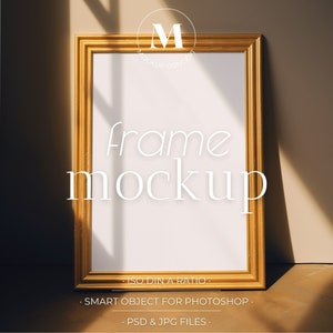 May include: A gold-colored picture frame mockup with a white background. The frame is on a wooden surface with a beige wall in the background. The text "frame mockup" is written in white below the frame. The text "ISO DIN A RATIO", "SMART OBJECT FOR PHOTOSHOP", and "PSD & JPG FILES" is written in white below the text "frame mockup".