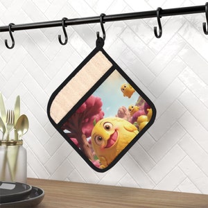 May include: A yellow pot holder with a cartoon image of three yellow creatures with smiling faces. The creatures are in a whimsical setting with pink flowers and a blue sky.