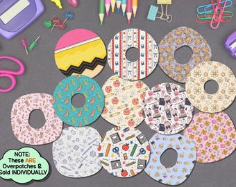 Peut inclure: Une collection de patchs adhésifs circulaires avec divers motifs sur le thème de l'école, incluant des crayons, des pommes, des dinosaures et des articles de papeterie. Chaque patch a une découpe centrale. Une bulle verte indique : NOTE: THESE ARE OVERPATCHES & SOLD INDIVIDUALLY.
