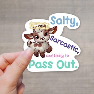 May include: A die-cut sticker featuring a cartoon goat with a halo. The goat is brown and white with large eyes. Text on the sticker reads "Salty, Sarcastic, and Likely to Pass Out."