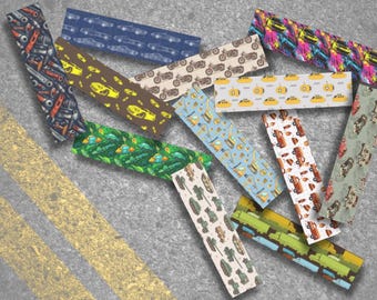 Peut inclure: Diverses bandes de tissu rectangulaires avec différents motifs. Les motifs incluent des voitures, des motos, des outils, des sous-marins, des camions et des instruments de musique. La palette de couleurs est variée, avec des nuances de bleu, vert, jaune, marron et rouge.