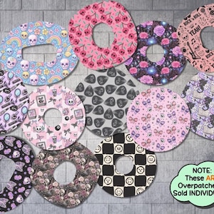 May include: A collection of overpatches with various designs, including skulls, cherries, roses, and bows. The color palette includes pink, purple, black, and blue. Some patches feature text like "Rock & Roll Yeah!" and the text "NOTE: These ARE Overpatches & Sold INDIVIDUALLY".