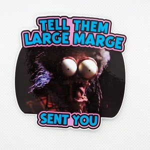 May include: A sticker with a pink and blue border featuring a cartoon character with large eyes and a shocked expression. The text "TELL THEM LARGE MARGE SENT YOU" is written in blue letters on a pink background.