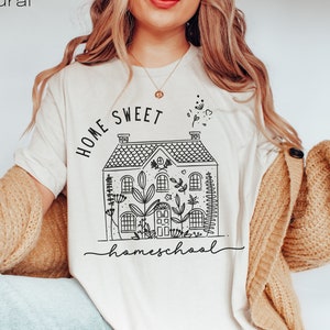 Pode incluir: Uma camiseta branca com um gr&aacute;fico preto de uma casa com o texto "Home Sweet Homeschool" impresso nela.