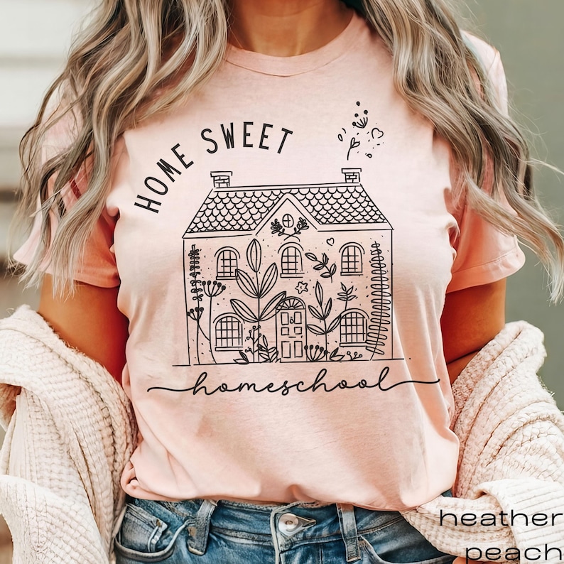 Pode incluir: Uma camiseta rosa com um gr&aacute;fico preto de uma casa com o texto "Home Sweet Homeschool" nela.