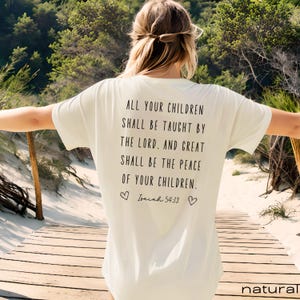 May include: White t-shirt with a black text quote on the back that reads "All your children shall be taught by the Lord. And great shall be the peace of your children. Isaiah 54:13".