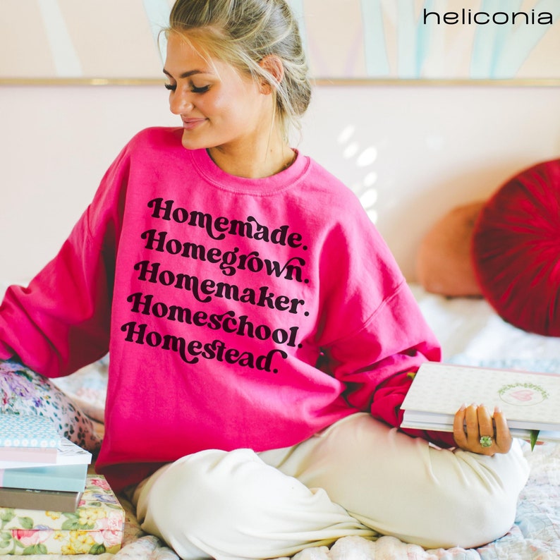 Op de afbeelding: Een roze sweatshirt met de tekst "Homemade. Homegrown. Homemaker. Homeschool. Homestead." in zwarte letters.