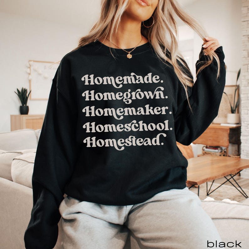 Op de afbeelding: Zwart sweatshirt met de tekst "Homemade. Homegrown. Homemaker. Homeschool. Homestead." in witte letters.