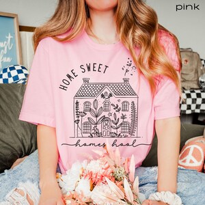Pode incluir: Camiseta rosa com um gr&aacute;fico preto de uma casa com o texto "Home Sweet Homeschool" nela.