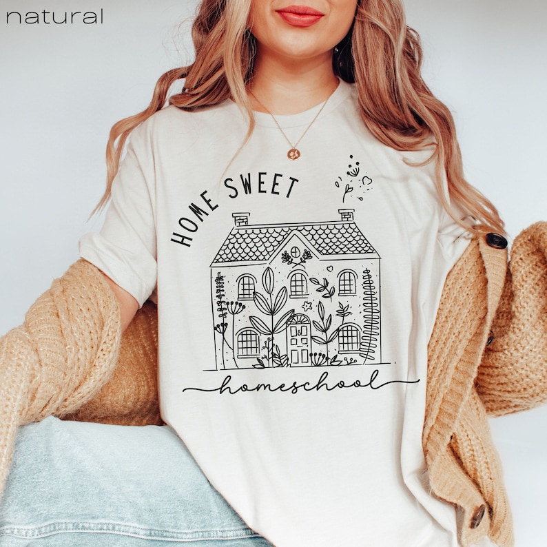 Pode incluir: Uma camiseta branca com um gr&aacute;fico preto de uma casa com o texto "Home Sweet Homeschool" impresso nela.