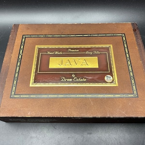 May include: A wooden box with a gold label that reads "Premium Hand Made Long Filler JAVA by Drew Estate".