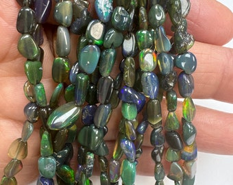 May include: A strand of dark green, black, and iridescent opal gemstone beads. The beads are irregularly shaped and have a smooth, polished finish.