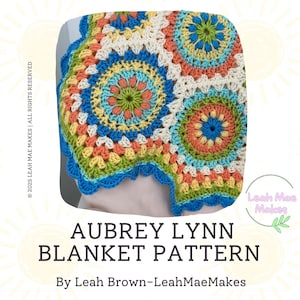 May include: A colorful, crocheted blanket with a circular pattern in shades of blue, orange, green, and cream. The blanket has a scalloped blue border. The text "AUBREY LYNN BLANKET PATTERN" is displayed below the blanket.