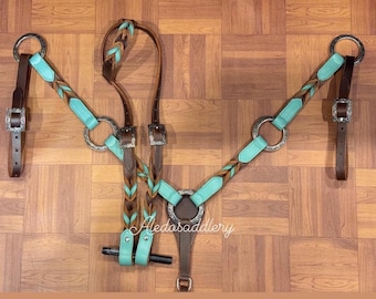 May include: A turquoise, brown, and silver horse breast collar and headstall set. The set features braided leather accents and silver-toned hardware. The design includes a breast collar, headstall, and connecting straps, all laid out on a wooden surface.