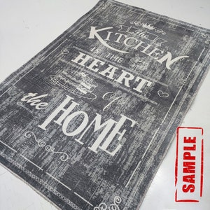 May include: A gray and white kitchen rug with the text "The Kitchen is the Heart of the Home" in a vintage style font.