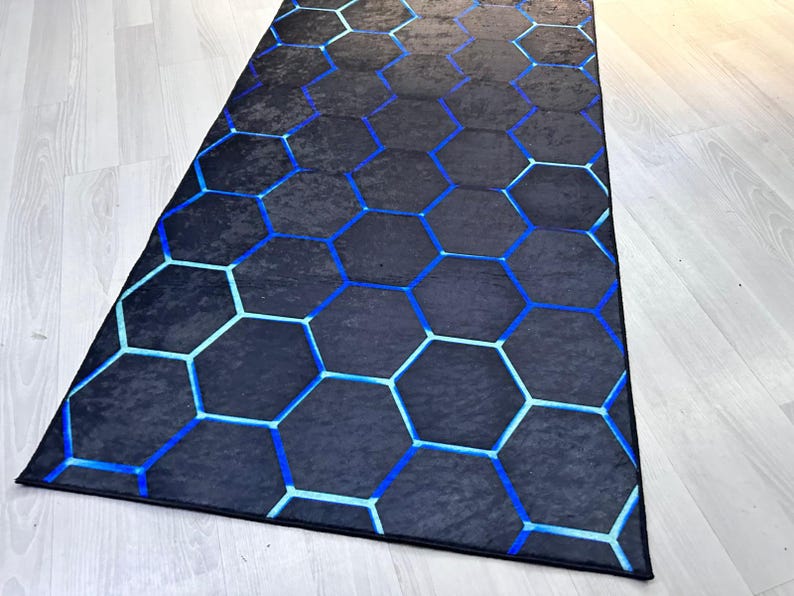 May include: A black and blue geometric rug with a hexagonal pattern. The rug has a modern design and is perfect for adding a touch of style to any room.