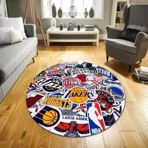 May include: Round rug with a white background and a colourful collage of NBA team logos, including the Lakers, Bulls, Celtics, and more.
