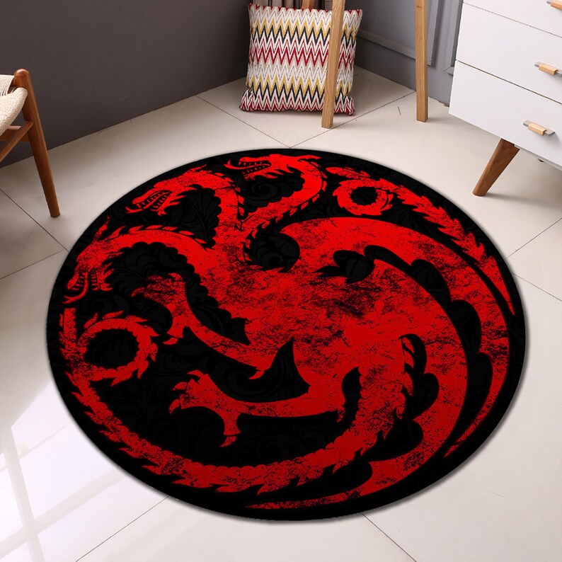 May include: A round red and black rug with a stylized dragon design. The dragon is a symbol of the House Targaryen from the popular television series Game of Thrones.