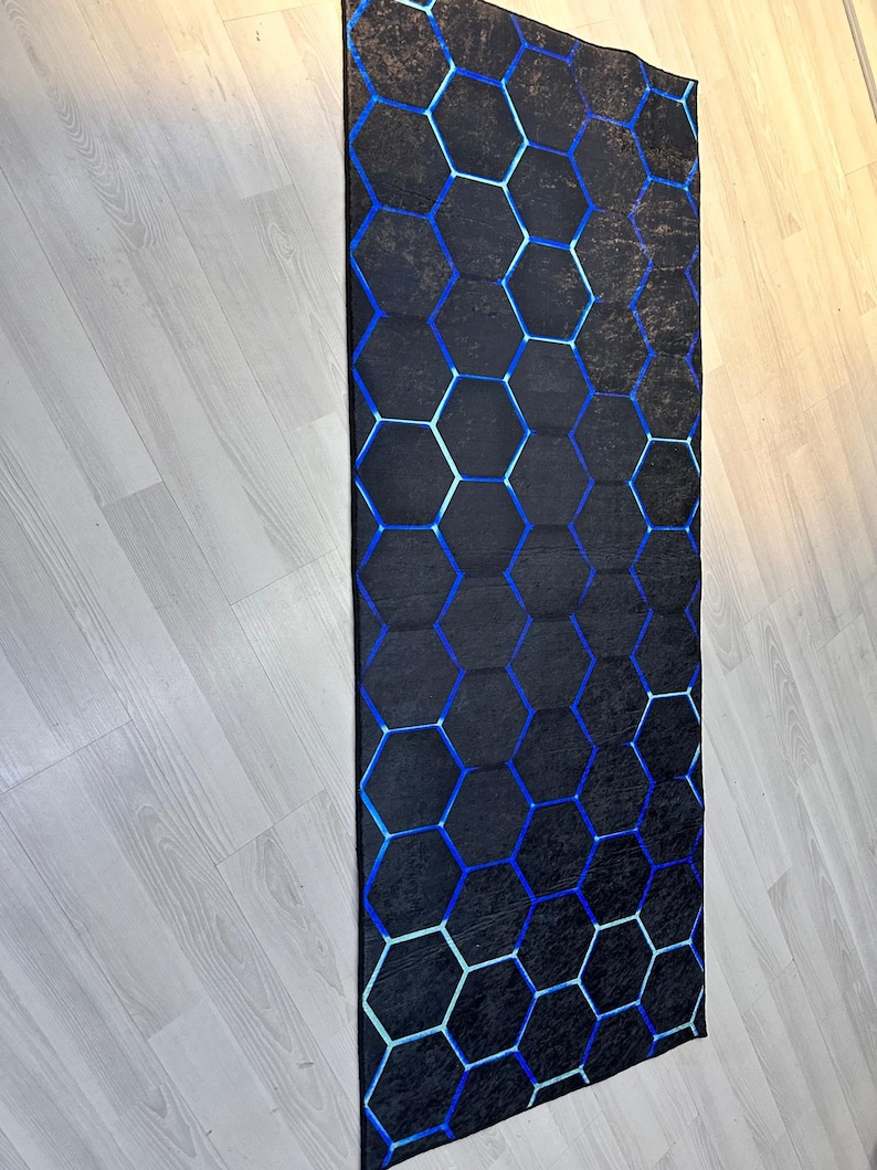 May include: A black and blue geometric rug with a honeycomb pattern. The rug has a distressed look, with faded areas in the black background.