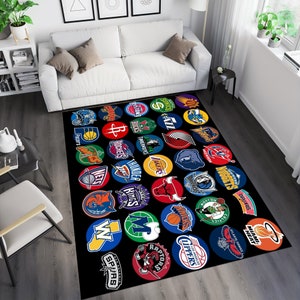 Pu&ograve; includere: Un tappeto nero e bianco con un motivo colorato di loghi delle squadre NBA. I loghi sono disposti in un cerchio e includono squadre come i Lakers, i Celtics e i Knicks.