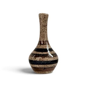 May include: A ceramic bud vase with a narrow neck and a bulbous base. The surface features a speckled beige finish with horizontal bands in dark brown and black. The glaze has a glossy sheen, and the overall form is symmetrical and slender.