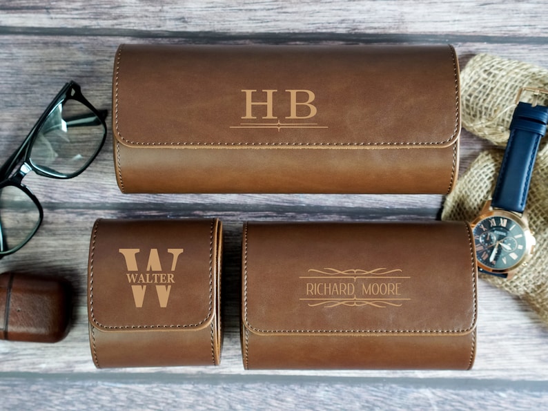 May include: Three brown leather watch boxes with personalized engravings. The top box has the initials "HB" engraved on it. The middle box has the letter "W" and the word "WALTER" engraved on it. The bottom box has the name "RICHARD MOORE" engraved on it.