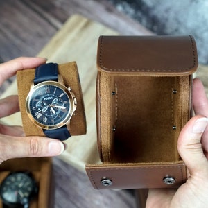 May include: A blue leather watch with a rose gold case and chronograph features. The watch is in a brown leather watch box.