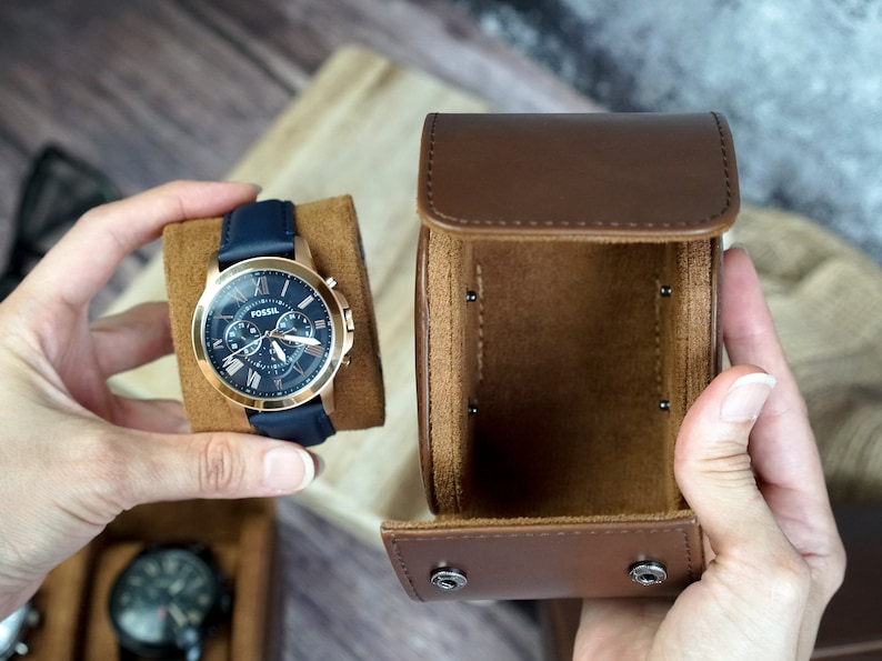 May include: A blue leather watch with a rose gold case and chronograph features. The watch is in a brown leather watch box.
