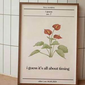 Peut inclure: Une impression encadrée avec une illustration botanique de fleurs d'anthurium rouges et de feuilles vertes. L'impression comporte le texte "lizzy mealpine", "i guess", "no. 7", "i guess it's all about timing", et "older | est. 04.05.2024".