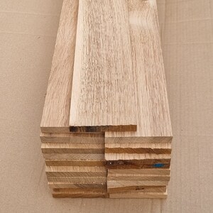 May include: A stack of unfinished, light brown wooden boards. The boards are stacked on top of each other and are all the same size. The boards are smooth and have a natural wood grain.