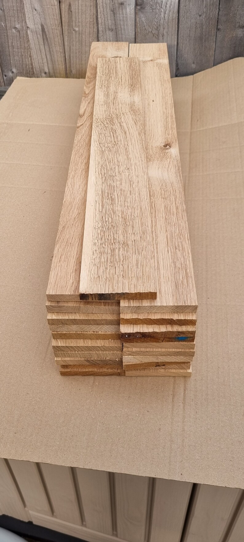 May include: A stack of unfinished, light brown wooden boards. The boards are stacked on top of each other and are all the same size. The boards are smooth and have a natural wood grain.