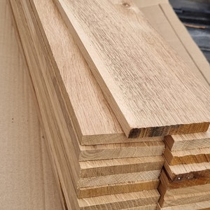 May include: A stack of unfinished, light brown wooden boards. The boards are stacked on top of each other and are ready to be used for a variety of projects.