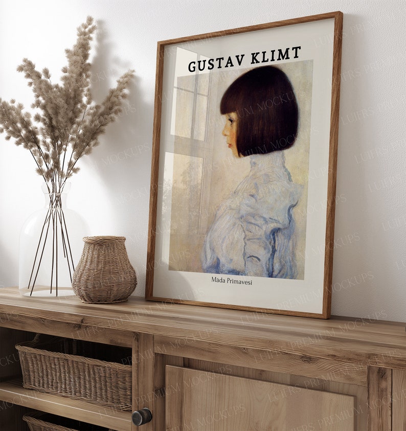 May include: A framed print of a painting by Gustav Klimt titled "Mada Primasvesi". The painting depicts a young girl with dark hair wearing a light blue dress, standing in front of a window.