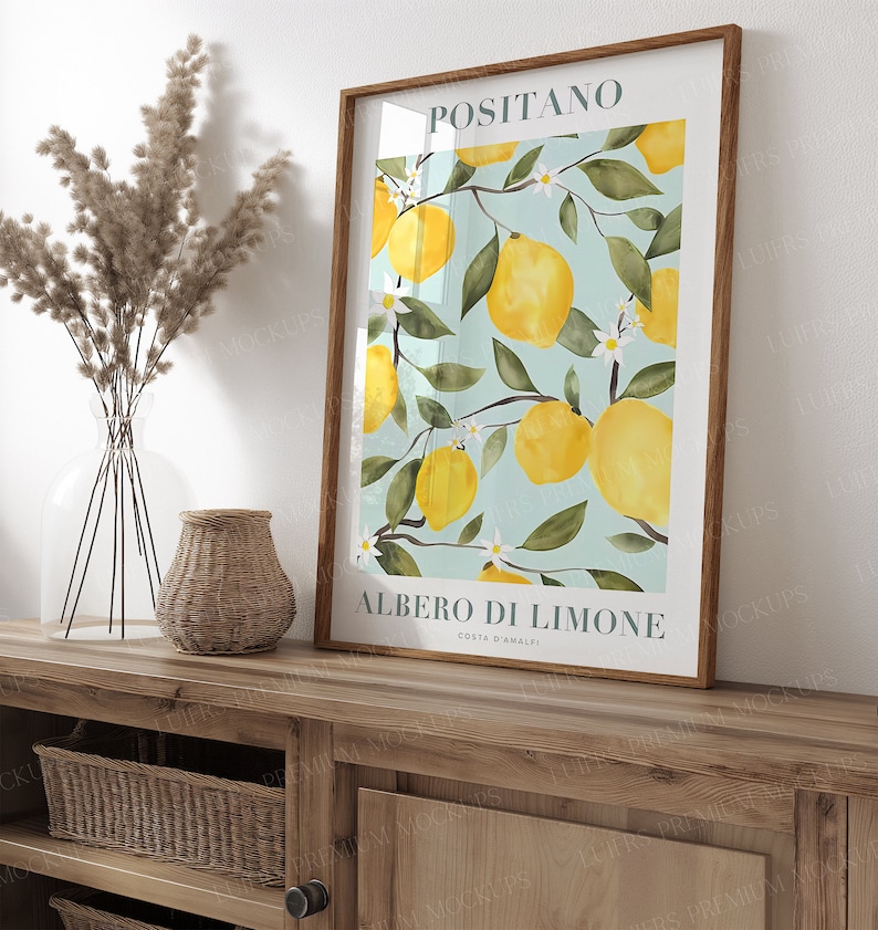 May include: A framed print with a watercolor illustration of a lemon tree with yellow lemons and white flowers. The print has the text "Positano" and "Albero di Limone Costa d'Amalfi" in a white font.