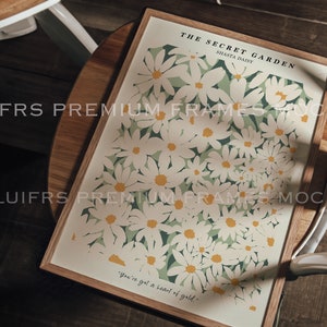 May include: A framed print with a floral design of white daisies with yellow centers on a green background. The text "THE SECRET GARDEN" and "SHASTA DAISY" is at the top of the print. The text "you're got a heart of gold." is at the bottom of the print.