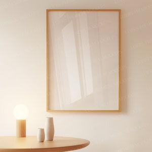 May include: A white wall with a gold framed picture, a wooden table with a lamp and two white ceramic vases. The lamp has a white glass globe.