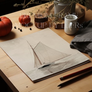 May include: A watercolor painting of a sailboat with white sails and a brown hull, set against a light gray background. The painting is framed and displayed on a wooden table with a cup, pumpkins, and other decorative items.