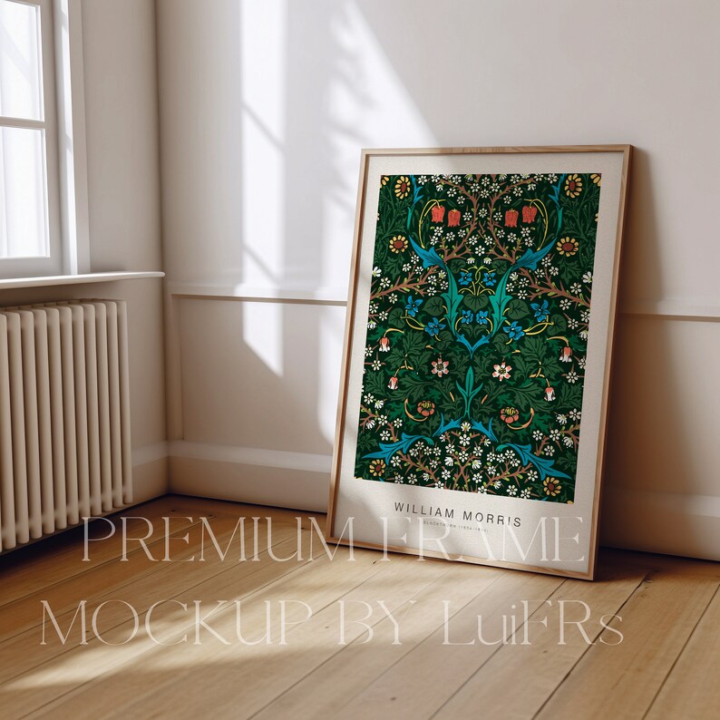 Op de afbeelding: Een ingelijste print van een bloemenpatroon in tinten groen, blauw, rood en wit. De lijst is gemaakt van natuurlijk hout en heeft een eenvoudig ontwerp. De print is getiteld "William Morris" en heeft een herhalend patroon van bloemen en bladeren.