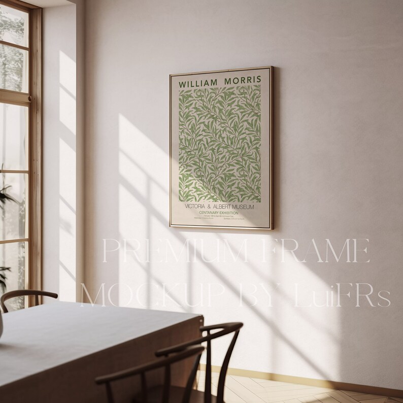 May include: A framed poster with a green and white floral pattern. The poster is titled "William Morris" and features the text "Victoria & Albert Museum, Centenary Exhibition". The poster is hanging on a white wall in a room with a wooden table and chairs.
