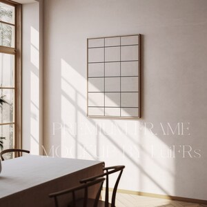 May include: A white wall with a light wood frame picture hanging on it. The frame is divided into a grid of squares. The picture is in a room with a white table and chairs.