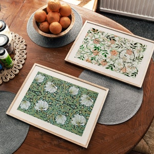May include: Two framed prints with floral patterns. The print on the left has white flowers on a green background. The print on the right has orange flowers on a white background.