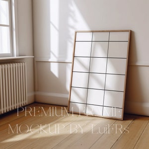 Op de afbeelding: Een groot, rechthoekig, houten frame met een witte passe-partout en een witte achtergrond. Het frame leunt tegen een witte muur in een kamer met een houten vloer. Het frame staat in de hoek van de kamer, en er is een radiator op de achtergrond.