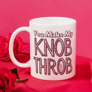 May include: White ceramic coffee mug with a red and black graphic that says "You Make My Knob Throb".