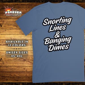 May include: A blue t-shirt with white text that reads "Snorting Lines & Banging Dimes".