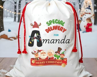 May include: White Christmas gift bag with red drawstring. The bag features the text "Special Delivery for Amanda" and a festive design including Santa, reindeer, and an elf. The words "Merry Christmas" are on a red banner.