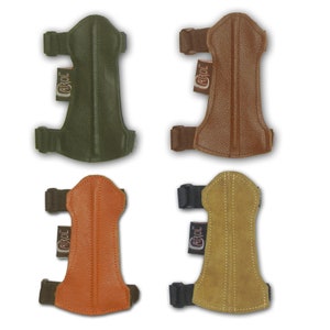 Puede incluir: Cuatro protectores de brazo de tiro con arco de cuero en diferentes colores: verde, marrón, naranja y beige. Cada protector tiene una correa negra y una etiqueta de cuero marrón con la palabra "CAROL" impresa.