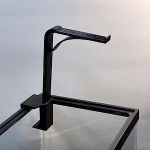 May include: A black aquarium light fixture with an adjustable arm and a clamp to attach to the tank. The fixture has a horizontal light bar and is designed to hold a light over an aquarium.