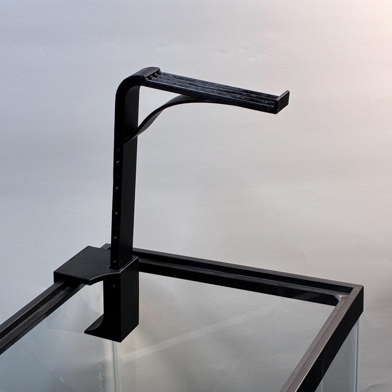May include: A black aquarium light fixture with an adjustable arm and a clamp to attach to the tank. The fixture has a horizontal light bar and is designed to hold a light over an aquarium.