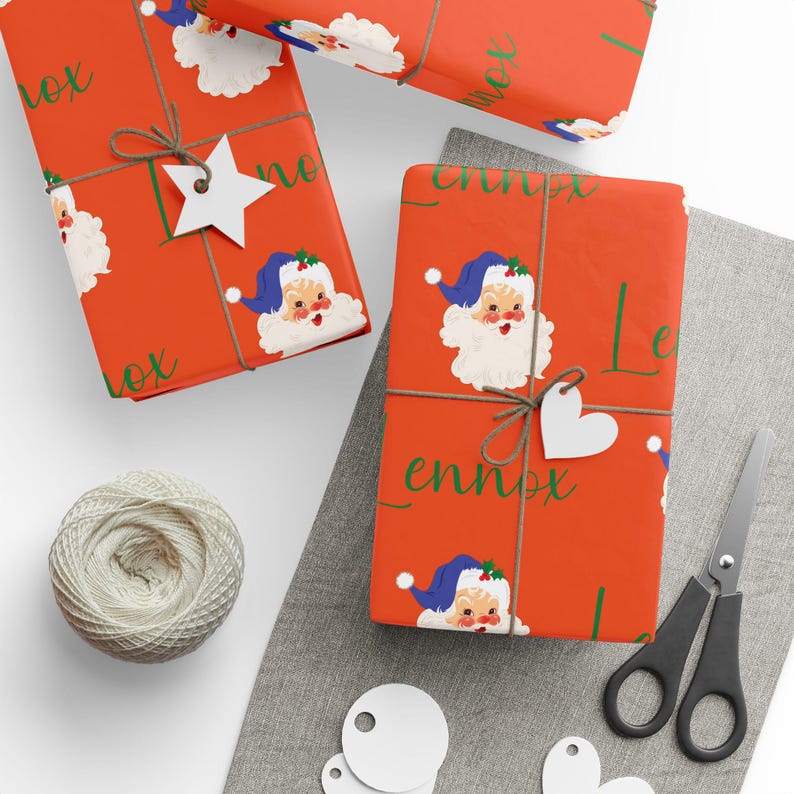 May include: Red wrapping paper with a repeating pattern of Santa Claus faces and the word "Lennox" in green script. The paper is wrapped around a gift box with a white star and a brown twine bow.