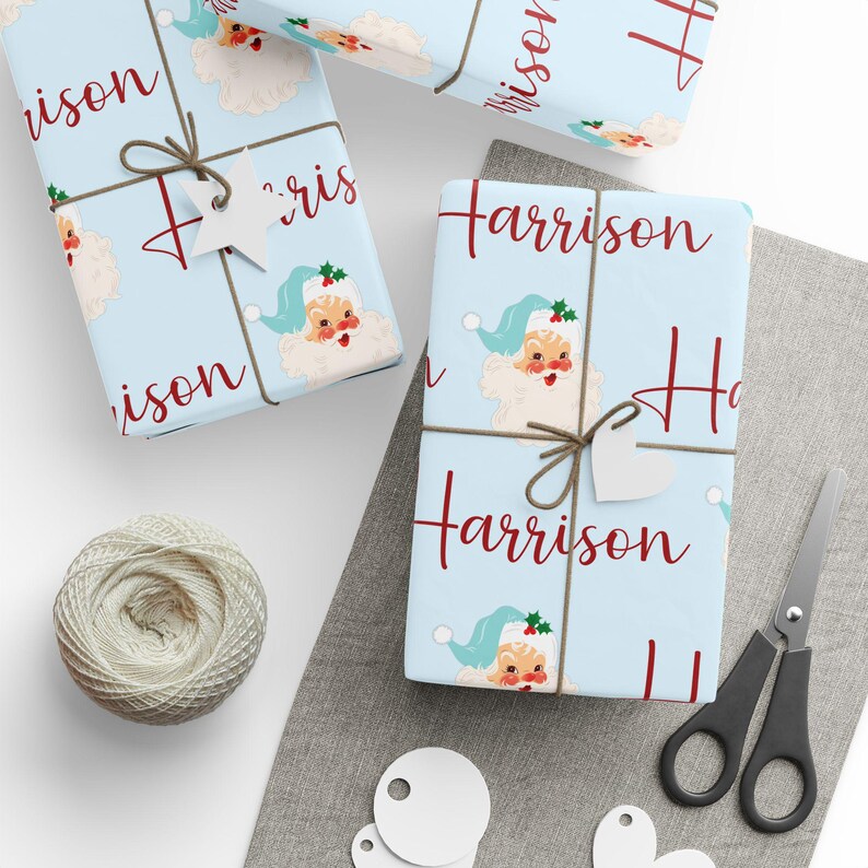 May include: Blue wrapping paper with a repeating pattern of a vintage Santa Claus illustration and the name "Harrison" in red cursive.